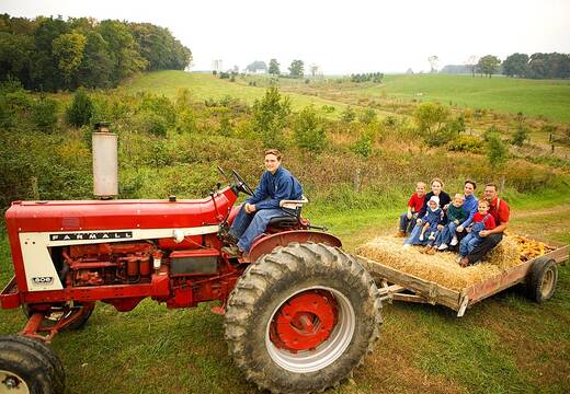 A tractor pulling a hay wagon with visitors on it