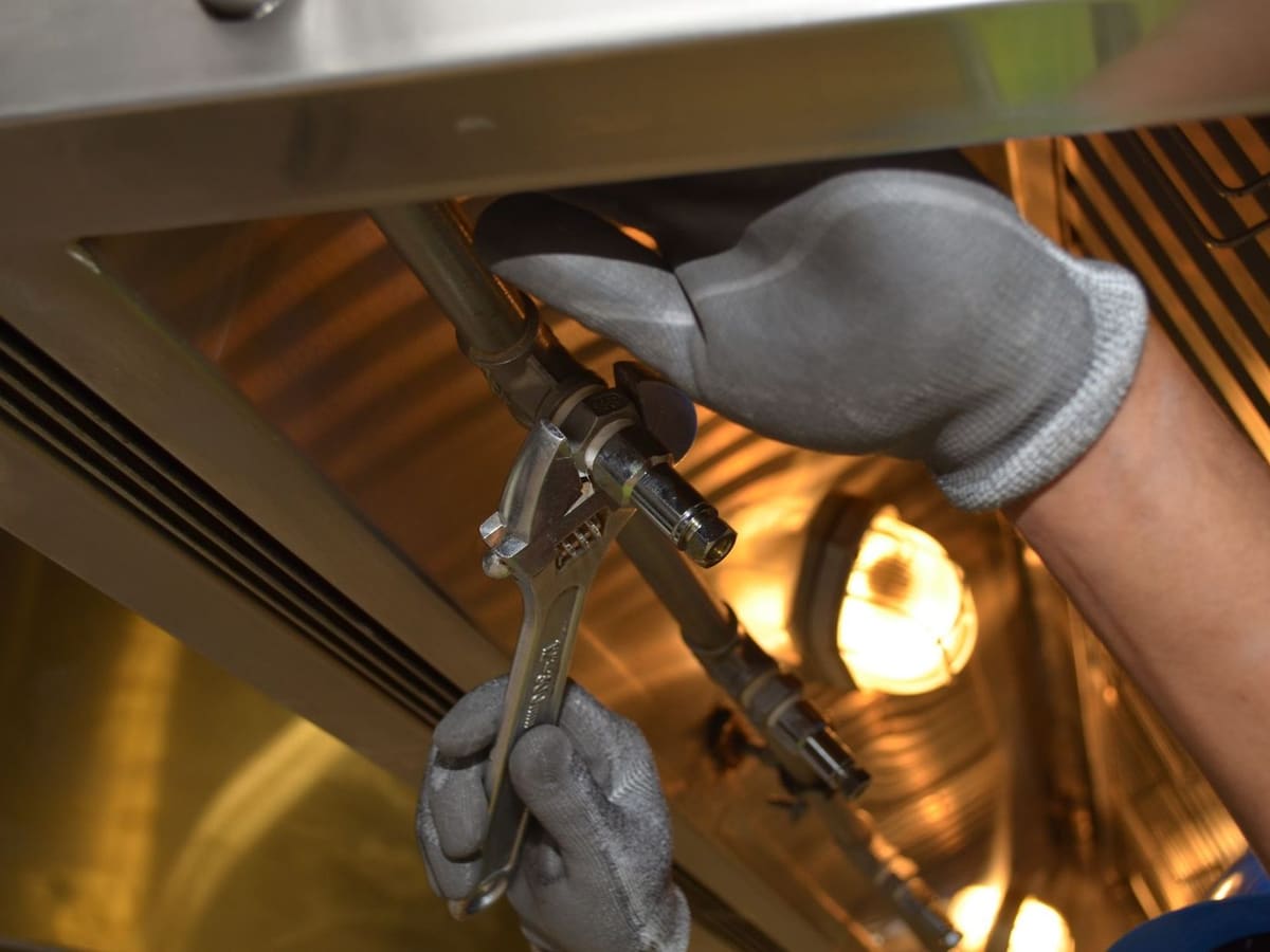 Plumber tightening a fitting under a sink