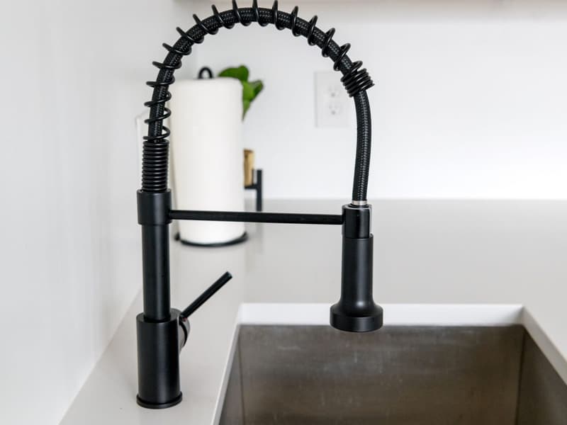 A newly fitted kitchen tap over a stainless sink